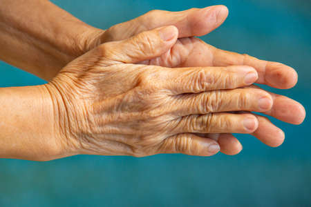 Senior woman's hands washing her hands in step 1 on bokeh blue pool  background, Close up & Macro shot, Selective focus, Prevention from covid19, Bacteria, healthcare concept, 7 step wash handの写真素材