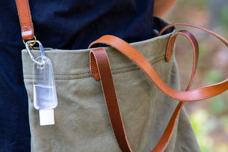 People's hands using portable wash hand sanitizer gel pump dispenser with alcohol gel sanitizer in bokeh green, Shoulder bag, Close up shot, Select focus, Prevention from covid19, Bacteria, Healthcareの写真素材