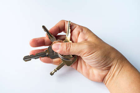 Woman's right hand use keys for lock or unlock in white background, Close up & Macro shot, Selective focus, Security conceptの写真素材