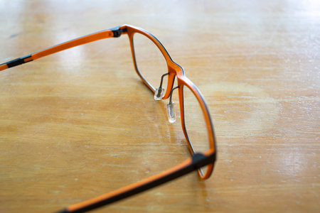 Orange & Black eyeglasses with ivory colour on wooden table background, Close up & Macro shot,...