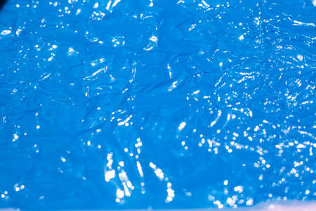 Bokeh blurred thin sheet of blue colour cellophane with shiny crumpled surface texture on white background, Abstract, Light & Shadow conceptの写真素材