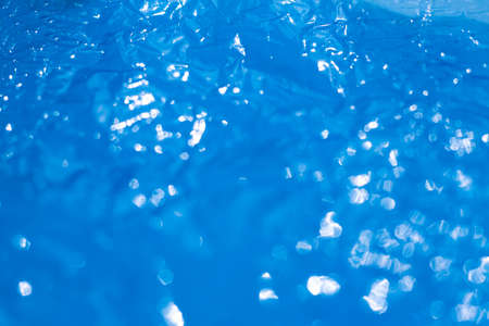 Bokeh blurred thin sheet of blue colour cellophane with shiny crumpled surface texture on white background, Abstract, Light & Shadow conceptの写真素材
