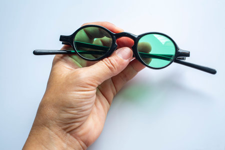 Woman's left hand cleaning black sunglasses by microfibre cleaning cloths, On white background,...