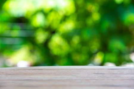 Empty curved wooden table texture, Green garden blurred bokeh background, Selective focusの写真素材