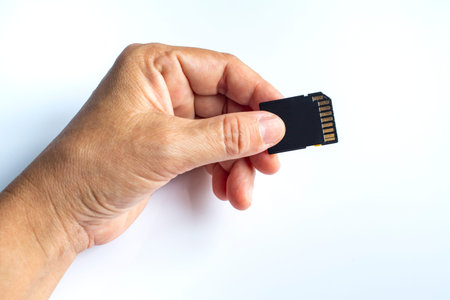 Woman's left hand holding SD card on white background, Close up and Macro shotの写真素材
