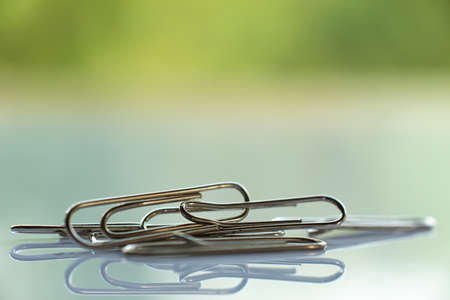Paper clip on white acrylic, Green garden background, Close up & Macro shot, Selective focus, Business, Education, Stationery conceptの写真素材