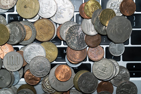 Coins of different countries on the keyboard in a laptop close-upの写真素材