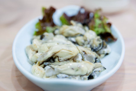 Fresh oysters on white plate in restaurant. Selective focus.の写真素材