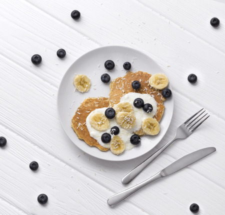 Sweet oatmeal pancakes with cream, blueberry and banana. Healthy Breakfast concept. Organic food on rustic wooden tableの写真素材