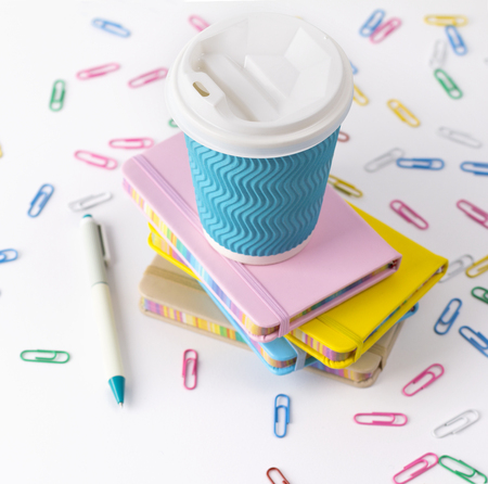Blue paper coffee cup, pen and notepads isolated on white background. Female office workspace conceptの写真素材