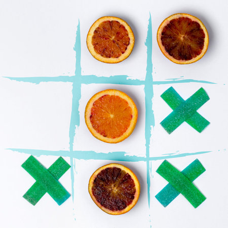 Tic tac toe made of jelly candy and blood oranges. Flat lay healthy vs junk food concept.