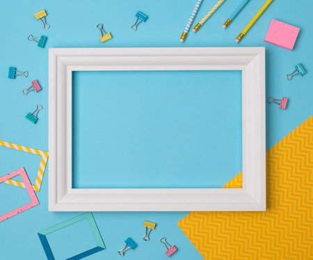 Flat lay empty frame and office supplies on blue pastel background
