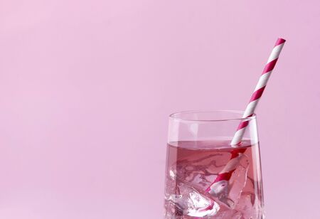 Summer refreshment drinks. Light pink rose cocktail on a pink background with striped pink straw.の写真素材