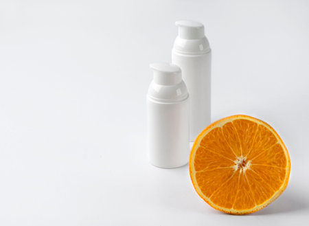 Two bottles of cosmetic cream with orange on white  background. Blank label for branding mockup....