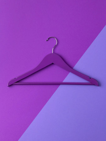 Top view flat lay single wooden hanger purple trendy background. Fashion feminine blog sale store...