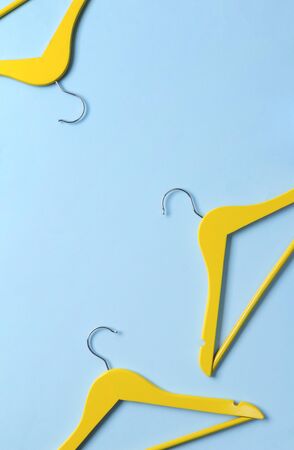 Minimalist top view flat lay yellow wooden hangers at blue background with copy space. Fashion feminine blog sale store promo design shopping concept.の写真素材