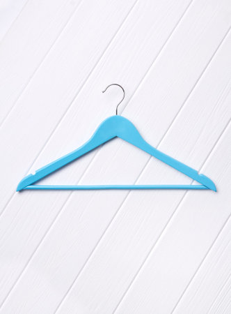 Top view flat lay single blue wooden hanger at wooden background. Fashion feminine blog sale store...