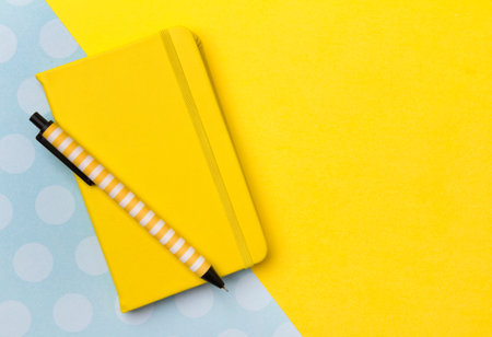 Pen and notepad at yellow turquoise creative background with copy space. Flat lay back to school...