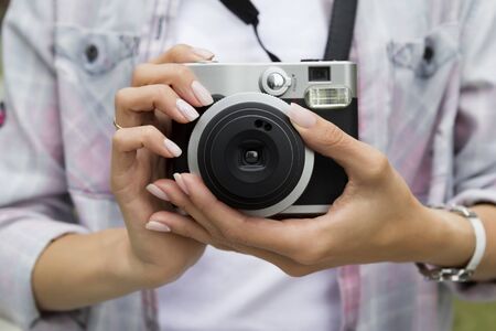 Young woman holding in hands old vintage camera. Girl photographer travel blogger conceptの写真素材
