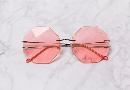 Modern fashionable coral sunglasses on white marble background. Minimal beach concept.