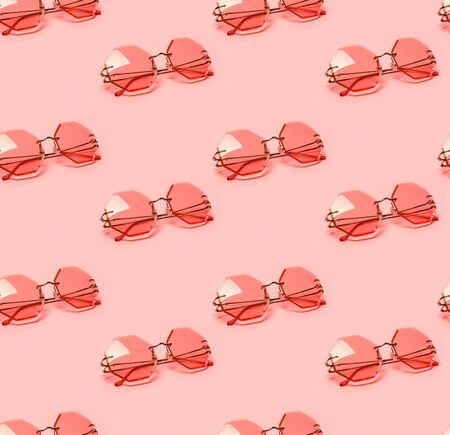 Seamless pattern with creative coral trendy sunglasses on pink pastel background. Minimal summer concept.  New color of the year 2019の写真素材