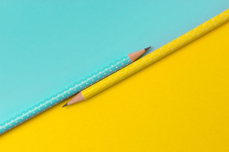 Top view of turquoise and yellow pencils on colorful creative paper background. Minimalist template with copy space.の写真素材