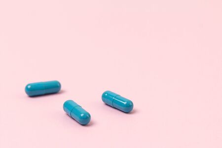 Blue pills at pink background. Empty place for text. Medicine health pharmacy pharmacology concept.の写真素材