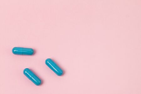 Blue pills at pink background.Flat lay. Empty place for text. Medicine health pharmacy pharmacology concept.の写真素材