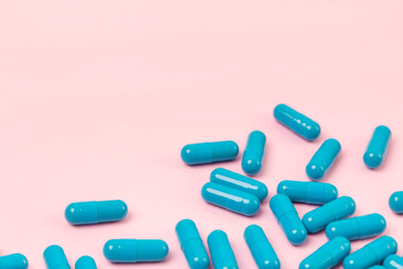Blue pills at pink background. Empty place for text. Medicine health pharmacy pharmacology concept.の写真素材