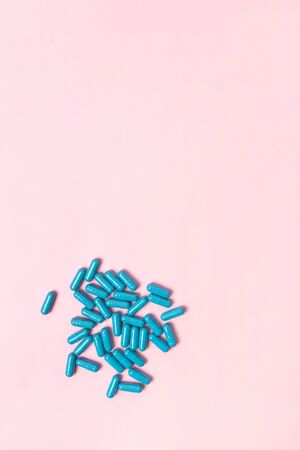 Blue pills at pink background.Flat lay. Empty place for text. Medicine health pharmacy pharmacology concept.の写真素材