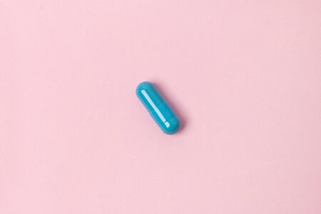 Blue pill at pink background. Flat lay top view. Medicine health pharmacy pharmacology concept.の写真素材