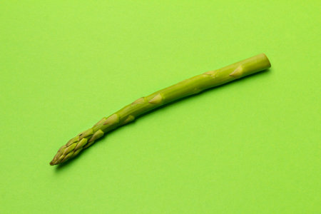 Fresh asparagus on green table background. Vegetarian food cooking concept