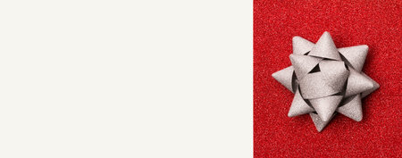 Silver gift bow on glitter red background with copy space. Christmas New Year Valentine's day...