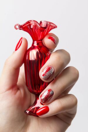 Christmas New Year manicure abstract nail design. Beautiful manicured woman's hand holding candy ornaments over white backgroundの写真素材