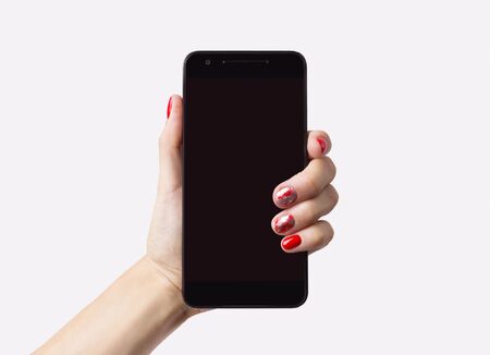 Christmas New Year manicure abstract nail design. Beautiful manicured woman's hand holding smartphone over white backgroundの写真素材