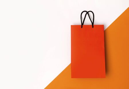 Orange paper shopping bag with black handles on the white background. Autumn sale conceptの写真素材