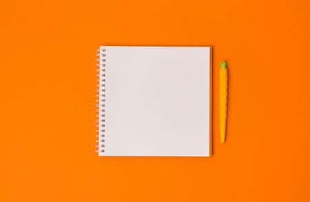 School office notebook on the orange background. spiral notepad on a table. Top view flat lay with copy spaceの写真素材