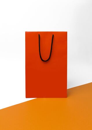 Orange paper shopping bag with black handles on the white background. Autumn sale conceptの写真素材