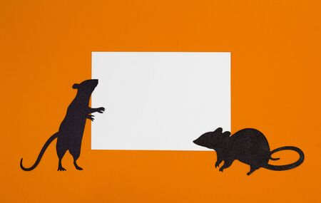 Sheet of paper at orange background with silhouettes of miceの写真素材