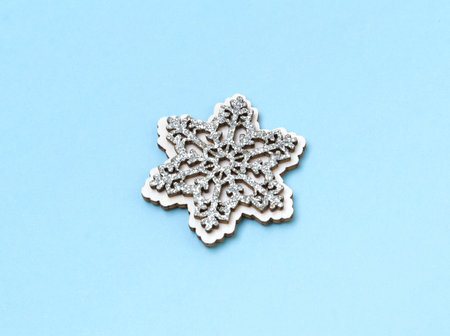 Wooden glittering snowflakes on blue pastel background. Christmas New Year holidays minimal...