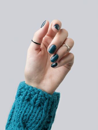 Manicured woman's hand in warm wool turquoise sweater. Fashionable autumn winter nail design.の写真素材