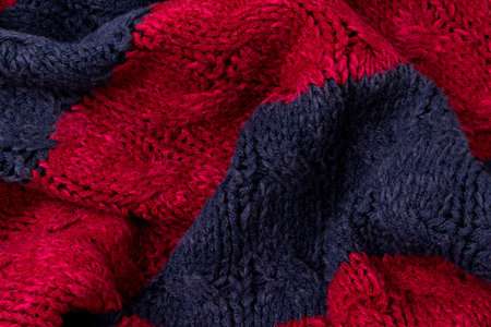 Texture of vinous with blue knitted fabric close up. Wool knitwear. Winter autumn sweater design