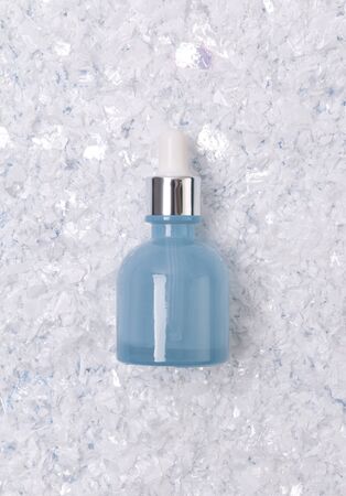Serum or oil in blue glass bottle with dropper on snowy background. Winter skin treatment conceptの写真素材