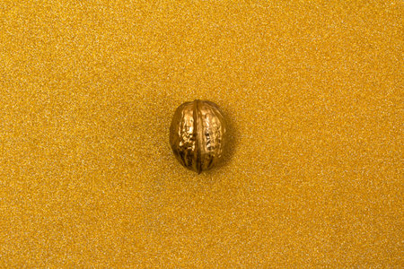 Painted golden walnut on glittering background. Christmas New year decor.