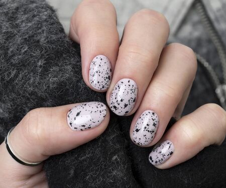Young adult woman's hands with pink nude fashionable nails on gray concrete background. Winter autumn nail design. Manicure, pedicure beauty salon concept.の写真素材