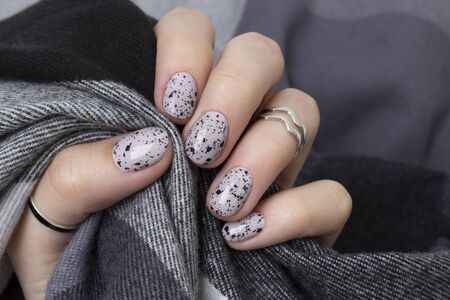 Young adult woman's hands with pink nude fashionable nails on gray concrete background. Winter autumn nail design. Manicure, pedicure beauty salon concept.の写真素材