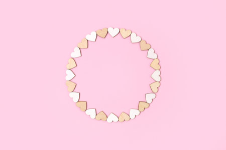 Frame made from wooden hearts on pastel pink background. Valentines Day flat lay top view. Love...