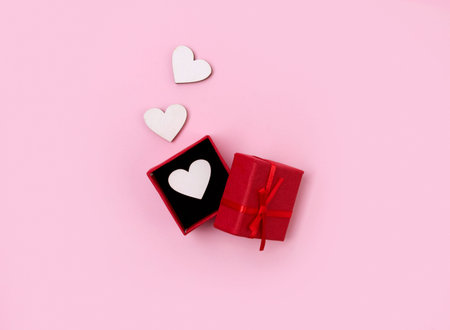 Open gift box with wooden hearts on pink background. Valentines Day flat lay top view. Love wedding...