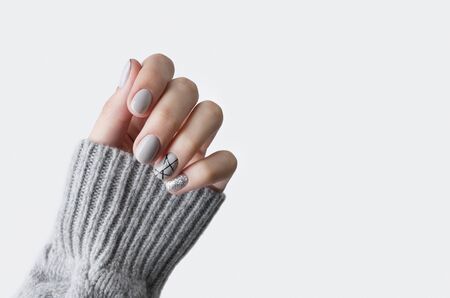 Females hand in gray knitted sweater with modern manicure close up. Winter christmas glittering nail designの写真素材