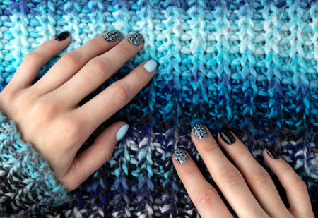 Womans hands with manicure in knitted wool sweater. Winter autumn fashionable blue nail art.の写真素材